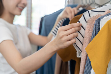 Obraz premium Choice of clothes, Nothing to wear asian young woman, girl hand in choosing dress, outfit on hanger in wardrobe in room closet at home. Deciding what to put on which one.