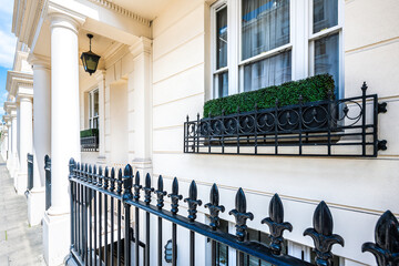 Pimlico, London terraced row house building white columns exterior old vintage historic traditional architecture and window with metal fence railing - Powered by Adobe