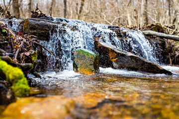Small waterfall river stream water flowing in Shamokin Springs Nature preserve hiking trail in Wintergreen Resort in Virginia closeup low angle ground level view
