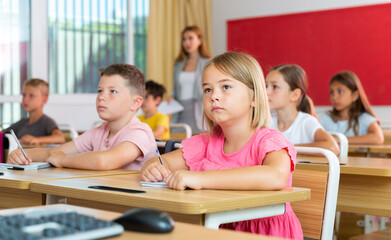 Portrait of tired schoolgirl sitting in classroom during lesson in elementary school