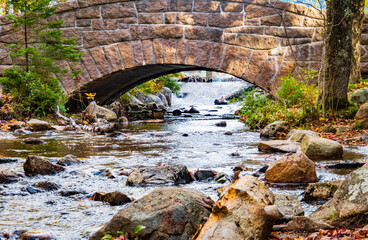 Fototapeta na wymiar water flowing from Jordon's Pond under historic stone bridge on footpath around the pond in Acadia National Park, Maine, USA 