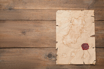 Sheet of old parchment paper with wax stamp on wooden table, top view. Space for design