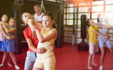Young children, boy and girl, working in pair mastering new self-defense moves at gym