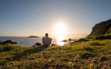 Man sitting watching sunrise at beach in New Zealand