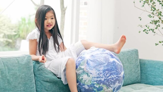 地球模様のボールに乗る女の子　エコロジーイメージ　SDGs
