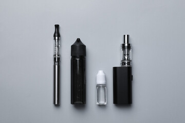 Electronic cigarettes and liquid solution on light background, flat lay