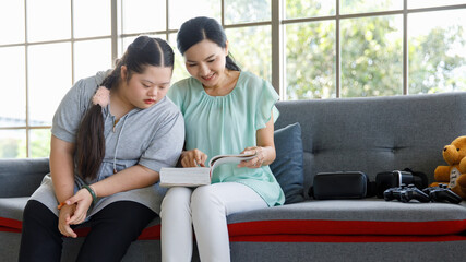 Asian young chubby down syndrome autistic autism little cute daughter sitting on cozy sofa smiling...