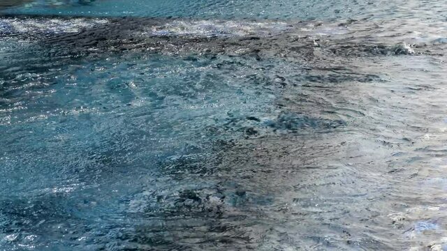 Transparent water surface in swimming pool. Deep liquid with light reflections. Hot tub of water used for hydrotherapy, relaxation or pleasure. Powerful jets for massage. Spas or jacuzzi