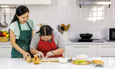 Asian lovely mother encouraging teaching young chubby down syndrome autistic autism pastry chef...