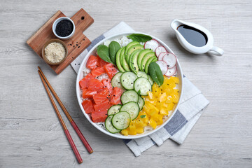 Fototapeta na wymiar Delicious poke bowl with salmon and vegetables served on wooden table, flat lay
