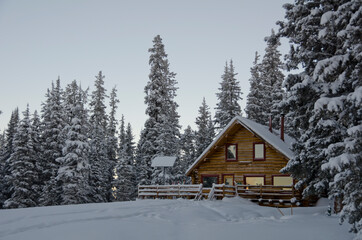 A snowy mountain cabin at dawn
