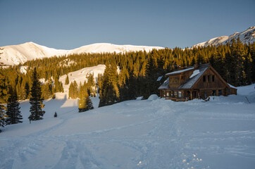 Sunrise over a snowy mountain cabin in winter
