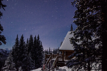 Starry skies over a cabin at night in the snowy mountains