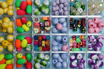 Box with different colorful beads on light blue background, top view