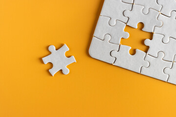 top view of white unfinish jigsaw puzzle on yellow orange background. business concept.