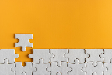 top view of white unfinish jigsaw puzzle on yellow orange background. business concept.