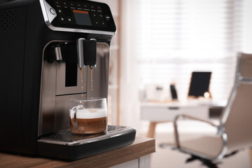 Modern espresso machine pouring coffee into cup in office. Space for text