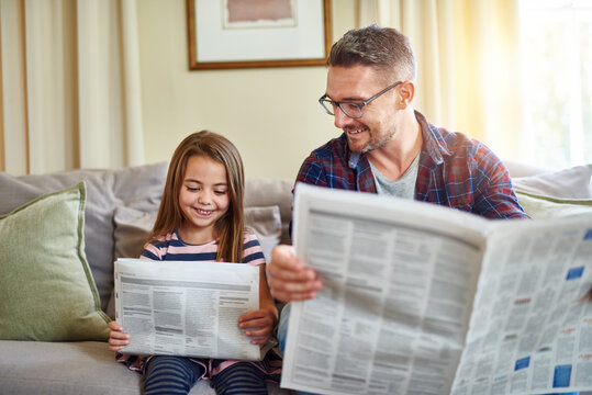 See anything interesting. Shot of a father and daughter reading the newspaper.