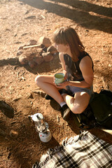 Coffee time at camp. Shot of a young woman drinking coffee while camping.
