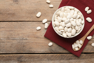 Raw white beans on wooden table, flat lay. Space for text