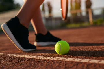 Crop tennis player on court with ball