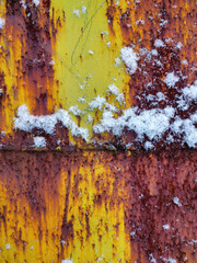 Rusty metal texture with orange paint and snow, vertical background, mobile photo with blur