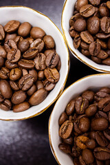 Coffee beans in white small coffee cups close-up on a dark background. Coffee grains in a cup top view. selective focus. High quality photo