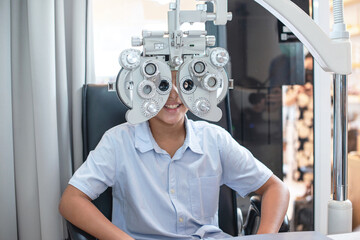 Indian boy doing eye test checking examination in optical shop, diagnostic ophthalmology equipment