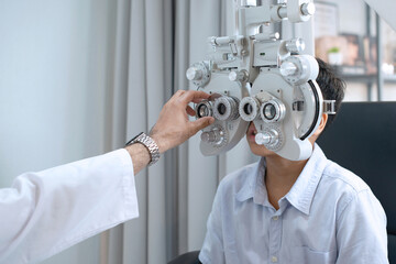 Indian boy looking through optical Phoropter during eye exam, The expert is testing the vision test...