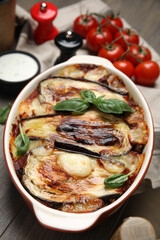 Delicious eggplant lasagna in baking dish on wooden table