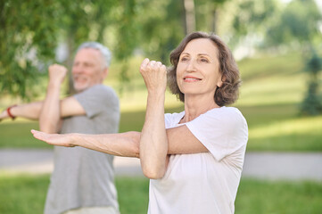 People having a yoga class in the park and stretching their arms