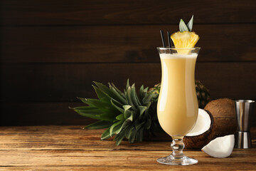 Tasty Pina Colada cocktail and ingredients on wooden table, space for text