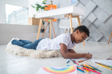 Obraz na płótnie Canvas Boy painting lying on rug on floor