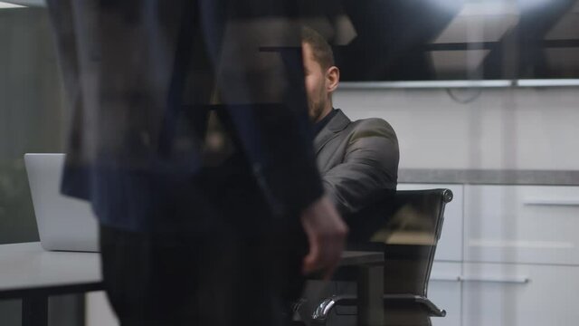 Young man manager talking on phone ay office, attractive woman colleague coming and sitting on table, seducing coworker