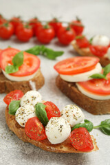 Delicious sandwiches with mozzarella, fresh tomatoes and basil on light grey table
