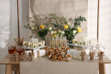 Delicious treats and glasses of drink on wooden table in room. Sweet buffet