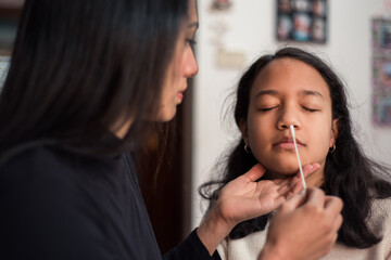 Mother ready to take a sample from her daughter's nose with the swab to perform the covid test at home.