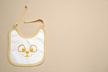 New baby bib on beige background, top view. Space for text