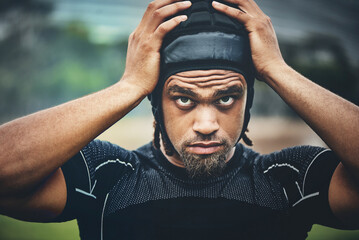 I'm ready to play some rugby. Cropped shot of a handsome young rugby player adjusting his headgear...