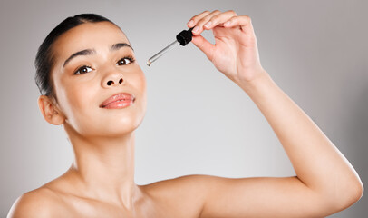 My secret potion for perfect skin. Studio shot of an attractive young woman applying serum to her face against a grey background.