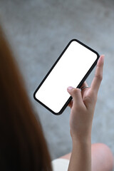 Close up view young woman hand holding smart phone with white empty screen.