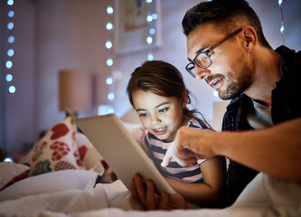 Which one shall we read tonight. Cropped shot of a father reading his young daughter a bedtime story on a tablet.