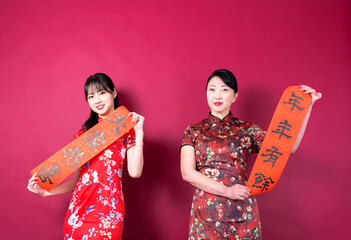 Asian mother and daughter in traditional cheongsam with copy space isolated on red background.The...