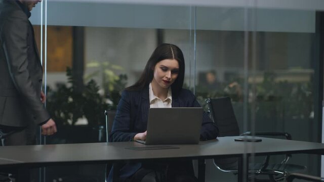 Flirt at workplace. Young businesswoman working on laptop at office, her male colleague coming and caressing her