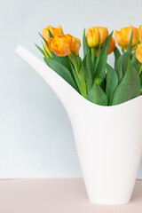 bouquet of yellow spring tulips in a white bailer closeup, copy space