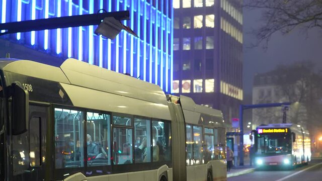 Electric buses charging in the city at night - Public transport, wide shot