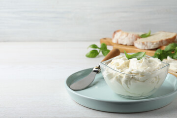 Tasty cream cheese with basil on white wooden table. Space for text