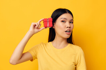 Charming young Asian woman in a yellow t-shirt holiday gift emotions studio model unaltered