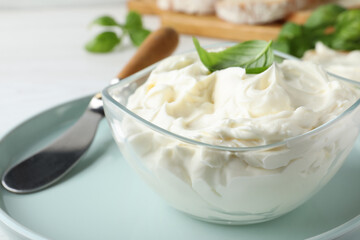 Tasty cream cheese with basil and knife on white table, closeup