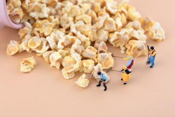 Miniature world workers pick up scattered popcorn